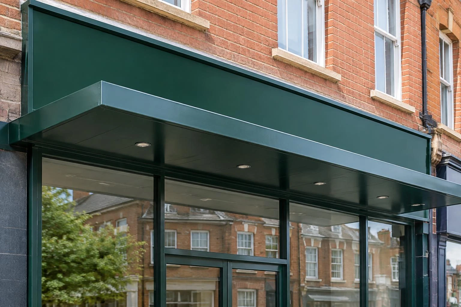 Commercial shopfront canopy beneath a blank green fascia sign