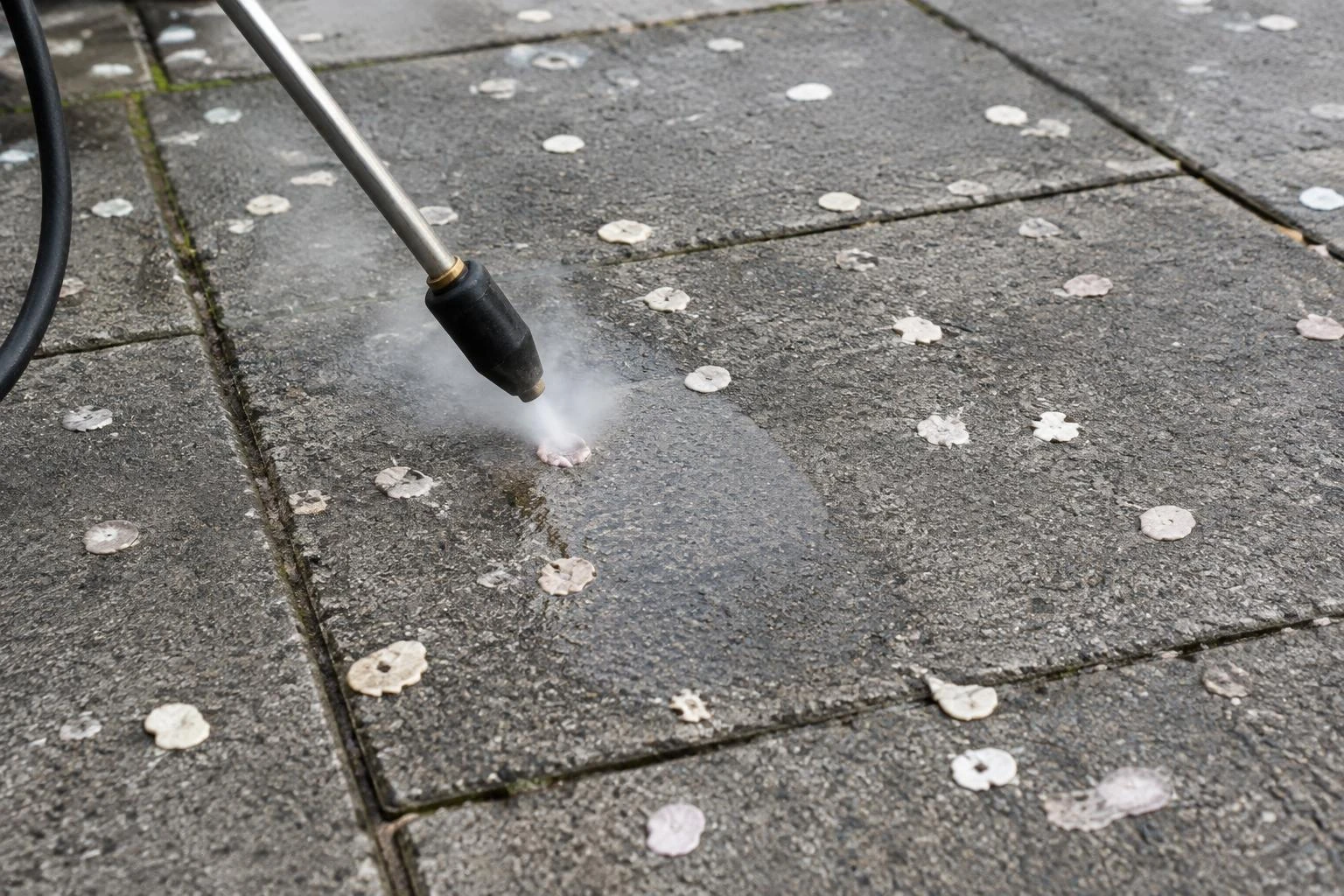 A cleaning lance removing flattened chewing gum from concrete paving