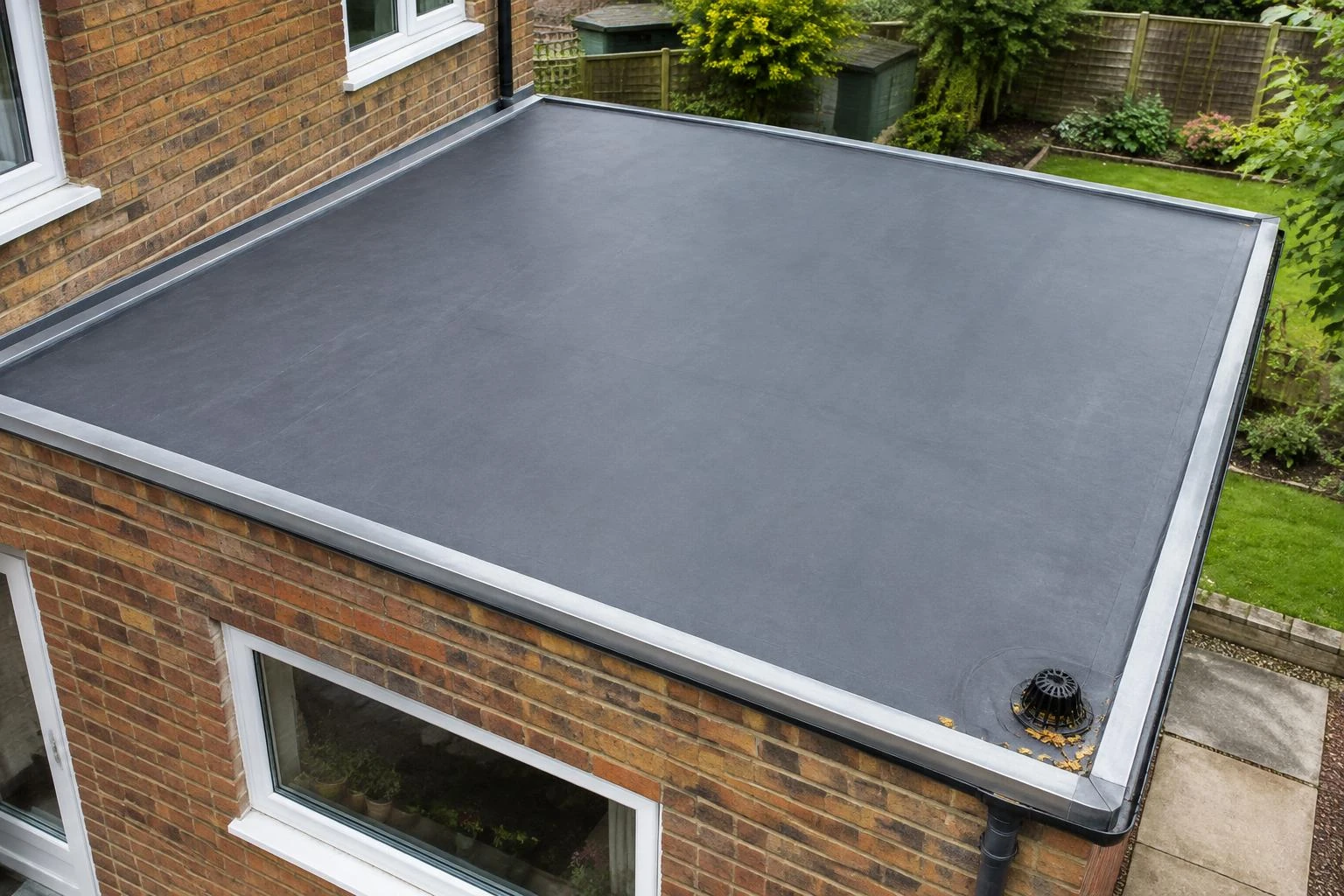 Flat EPDM extension roof with edge trim and a corner rainwater outlet